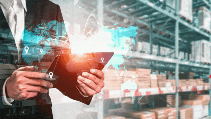 Businessman using tablet with global supply chain network overlay in warehouse