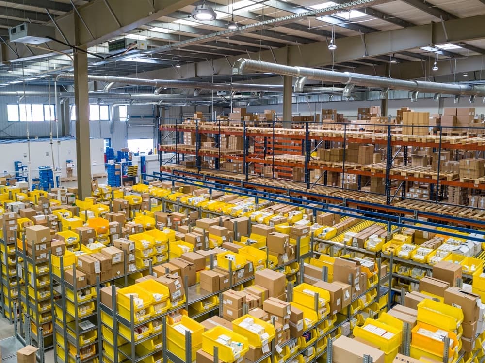 Large warehouse facility with organized shelving systems and yellow storage containers for inventory management