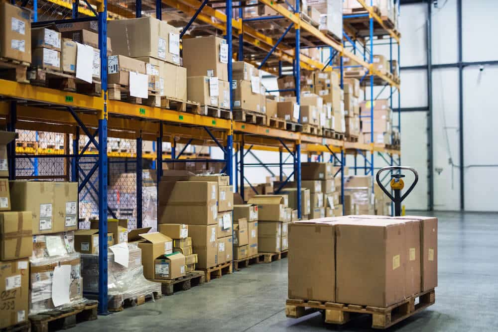 Warehouse interior with pallet truck and stacked cardboard boxes on industrial shelving