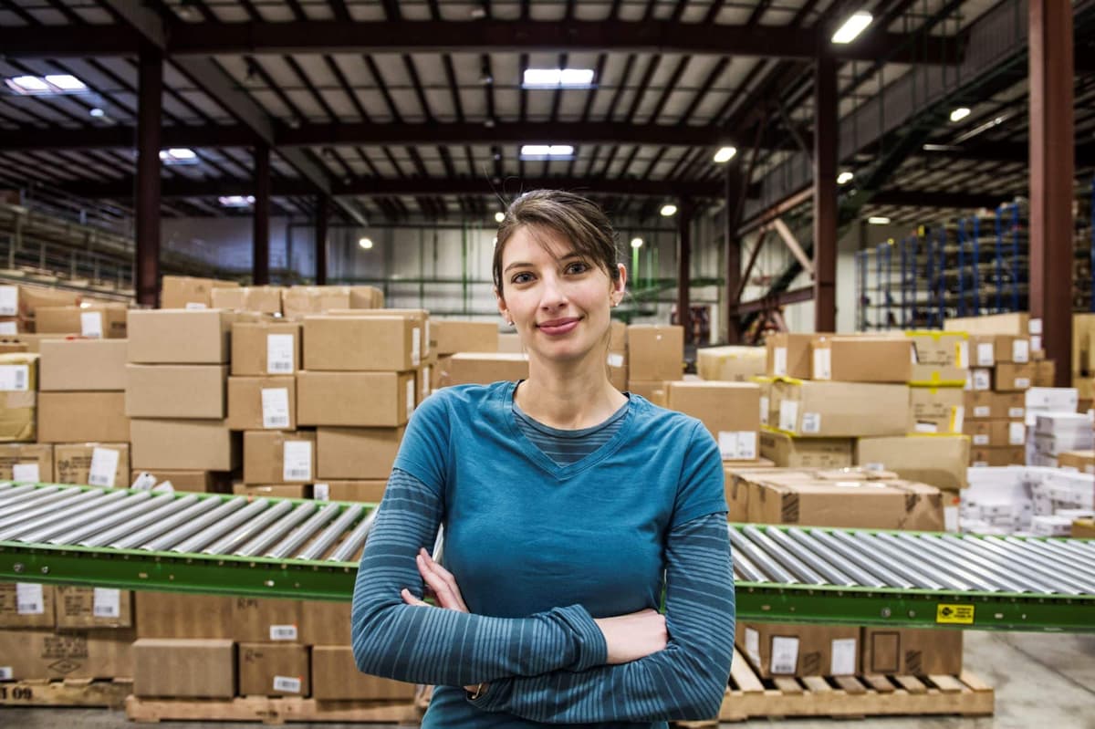 a-caucasian-female-warehouse-worker-in-a-distribution warehouse in front of a conveyor