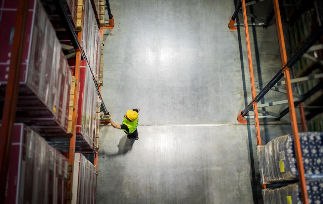 Warehouse worker in safety vest scanning package in industrial storage facility