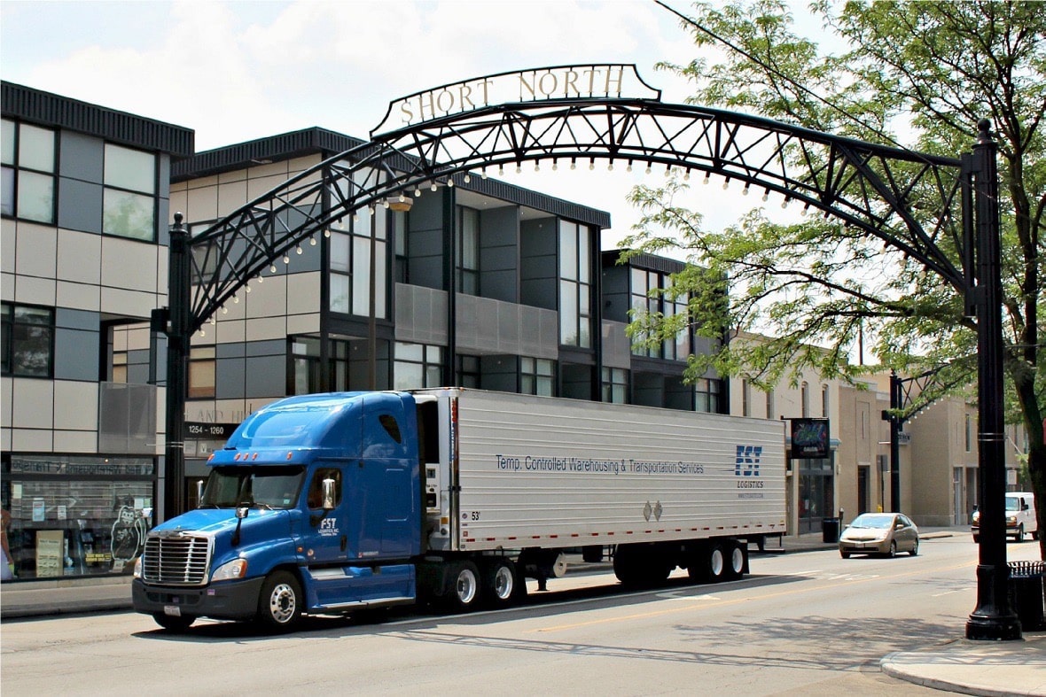 Blue semi-truck with refrigerated trailer driving under Short North Gateway arch in Columbus
