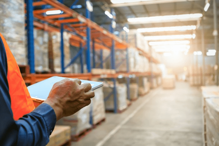 warehouse worker reviewing reports on tablet