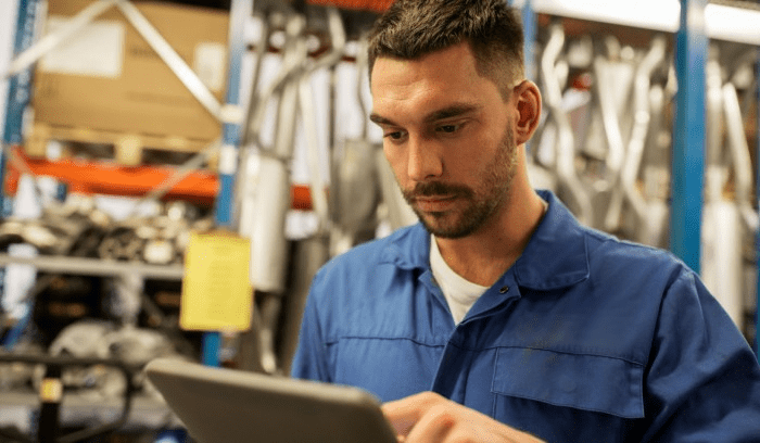 man looking at a tablet in automotive warehouse