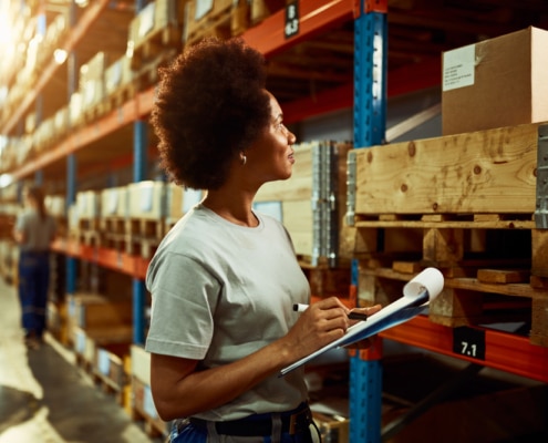 woman looking at the shelves with a clipboard