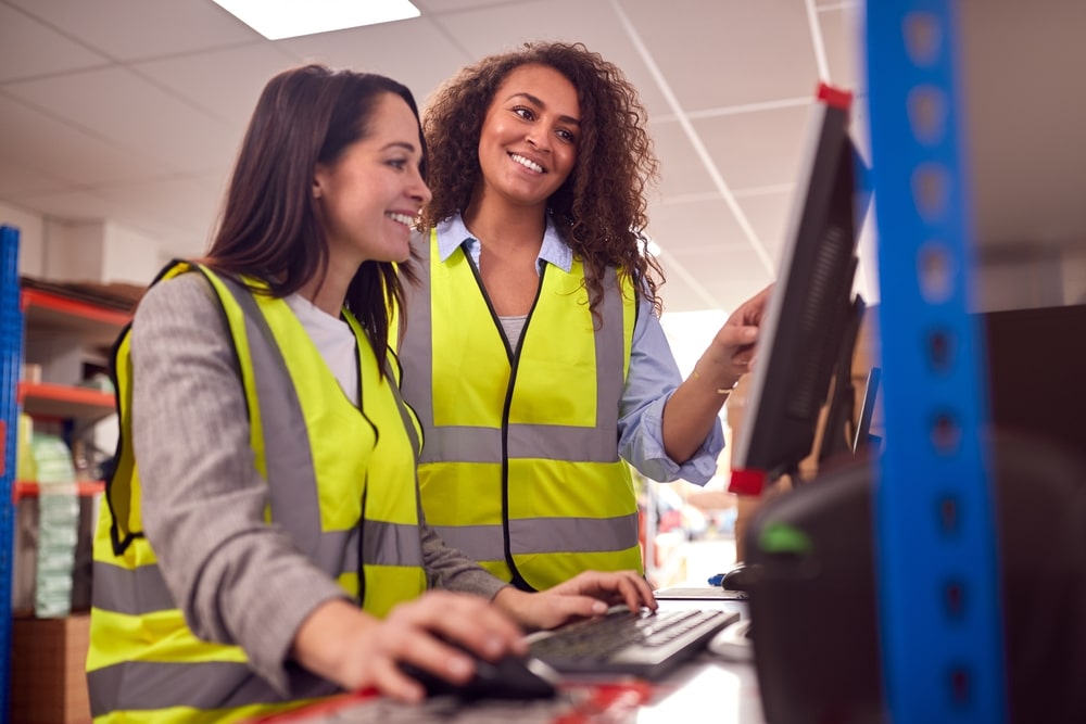 2 warehouse workers looking at a computer screen