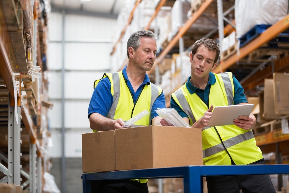 2 warehouse workers putting away a box of inventory