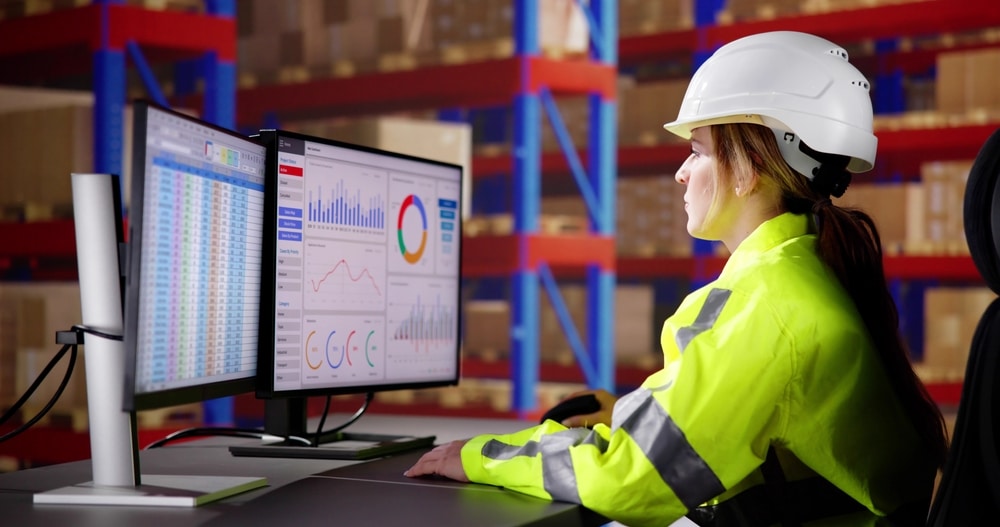 warehouse worker looking at computer screens showing warehouse KPIs using charts and graphs