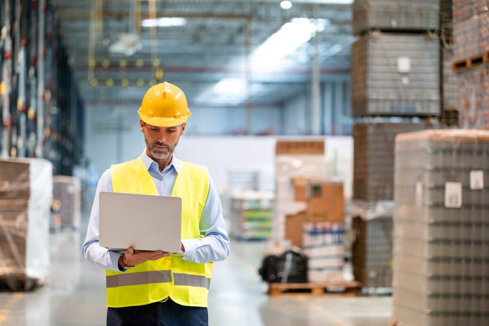 man holding a laptop in a warehouse