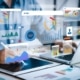 person on a laptop and tablet with icons floating in the showing what they are working on different charts and graphs