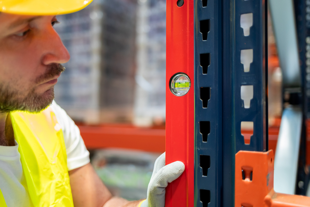 male worker using level to check warehouse shelving assembly