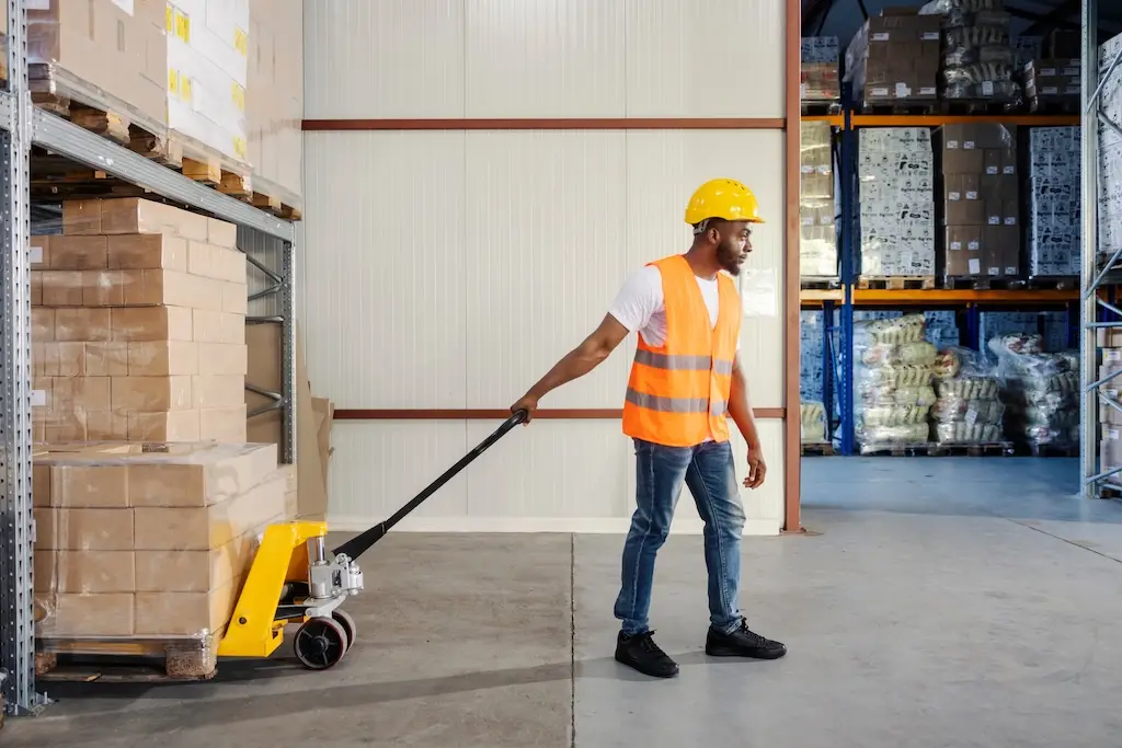 african american worker pulling pallet in warehouse