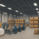 "Wide warehouse interior segmented into zones for materials, assembly, finished goods, and maintenance tools."