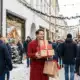 Person in red coat carrying holiday gift boxes during festive winter shopping season