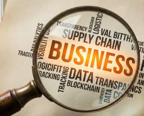 Magnifying glass highlighting "business" in word cloud showing supply chain visibility terms