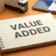 Spiral notebook displaying "VALUE ADDED" text on orange background for 3PL services