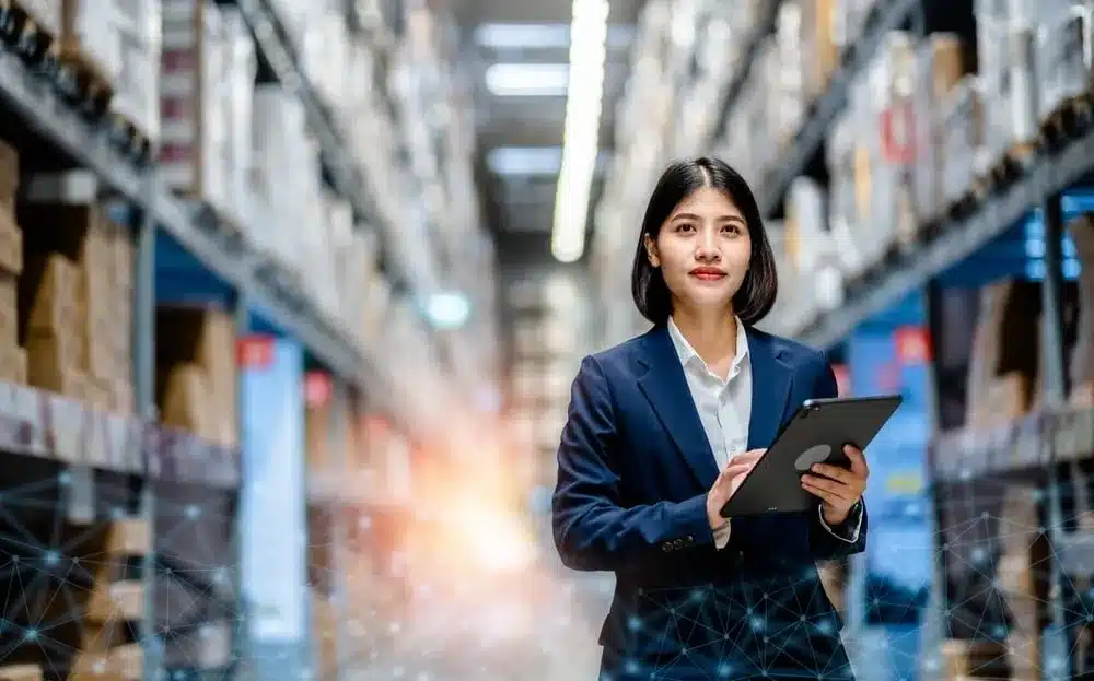 warehouse manager looking forward, holding a tablet with interconnected lines overlaid on the bottom